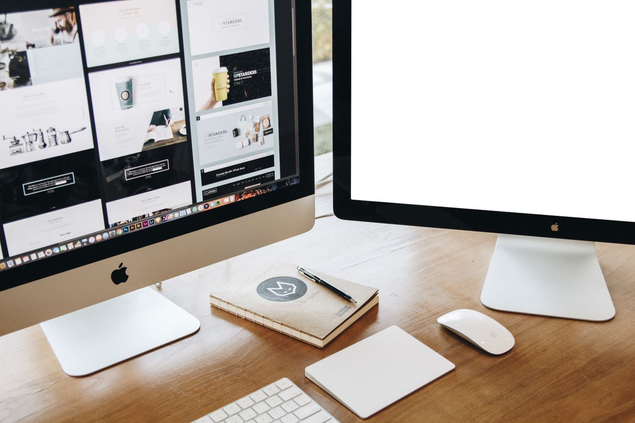 High-angle view of a sleek workstation with dual monitors, a keyboard, a mouse, and contemporary accessories.