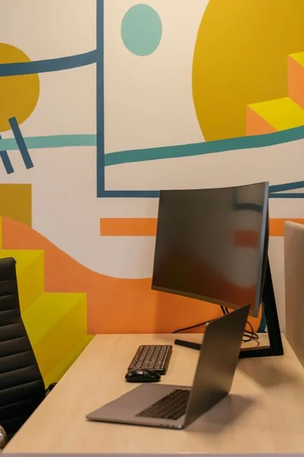 Un espace de travail contemporain avec deux écrans d’ordinateur présentant des projets de conception web, mettant en avant la technologie et la productivité.