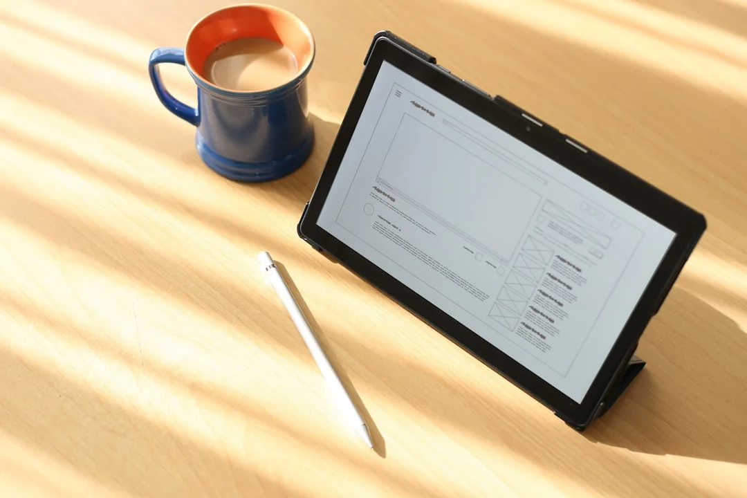 Person using a laptop and graphic tablet for digital design work in a home office.